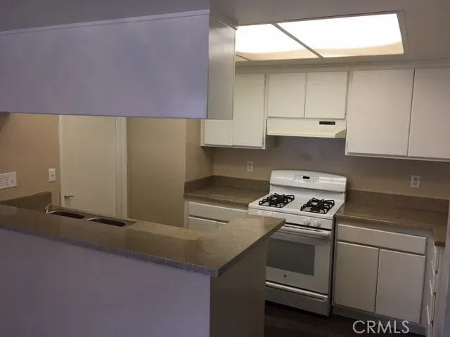 a kitchen with granite countertop a sink a stove and cabinets