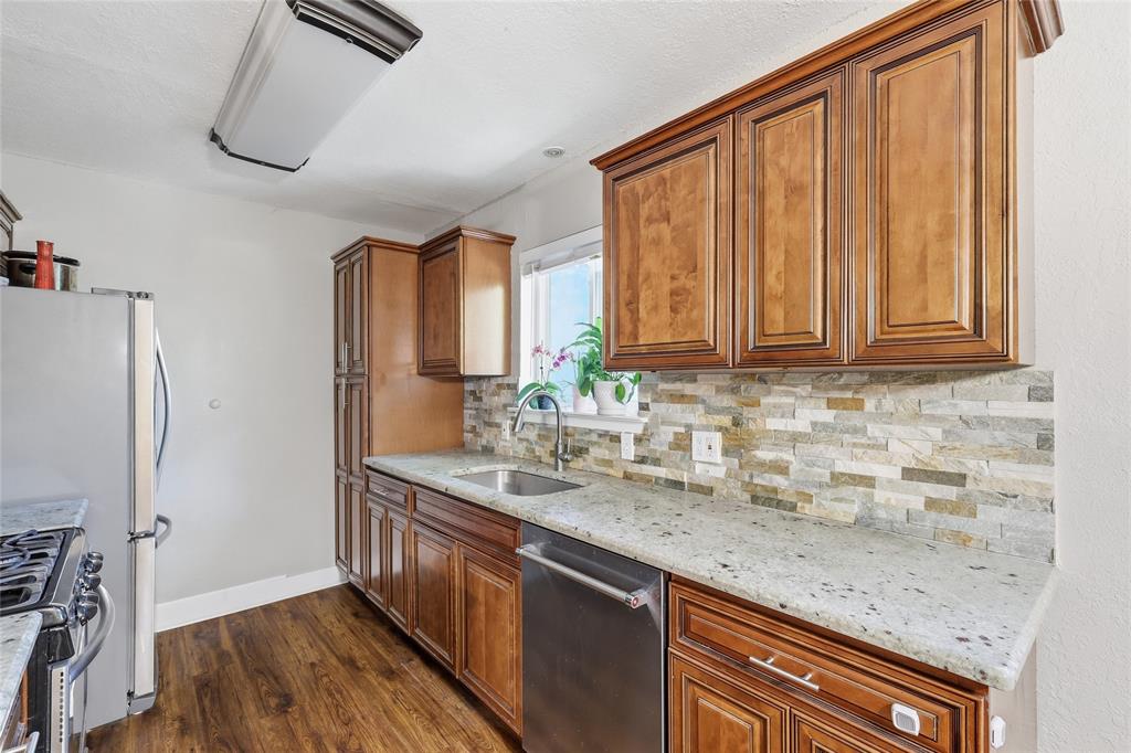 16 Coffee Tavern Road Bedford, TX 76022 - Photo 9 of 24 Kitchen featuring wood-finish cabinetry, light-toned countertops, and a stacked stone-look backsplash