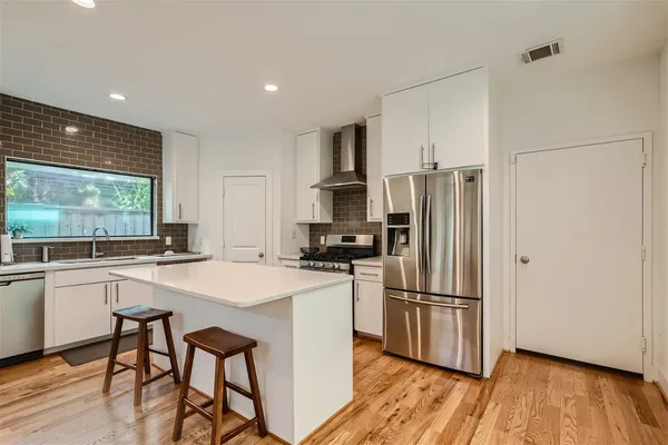 a kitchen with stainless steel appliances granite countertop a refrigerator a stove a sink and a refrigerator with wooden floor