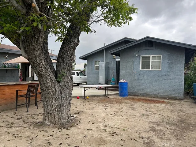 a view of a house with large trees and wooden fence