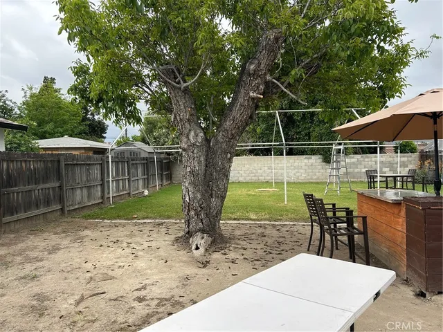 a view of a backyard with table and chairs under an umbrella