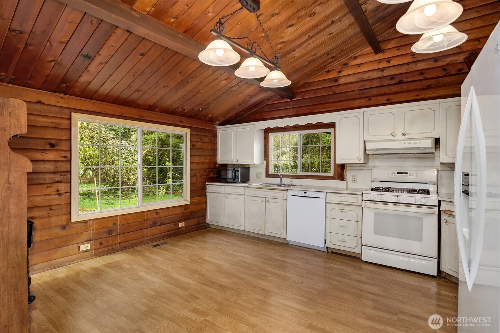 10862 Falk Road Northeast Bainbridge Island, WA 98110 - Photo 18 of 34 a kitchen with stainless steel appliances granite countertop a stove a sink dishwasher and white cabinets with wooden floor