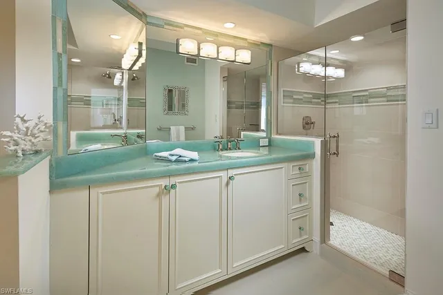 a bathroom with a granite countertop sink a mirror and a shower