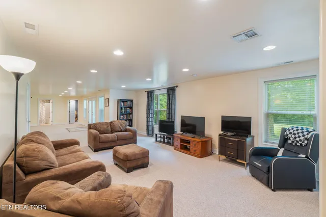 a living room with furniture flat screen tv and large windows
