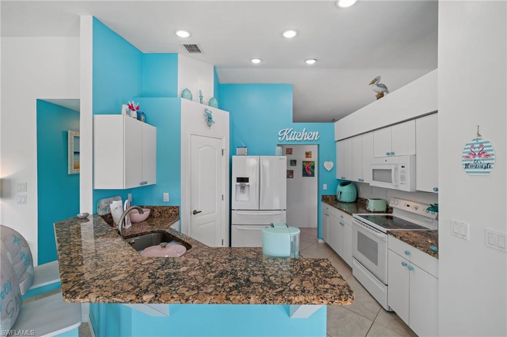 1408 Southwest 23rd Street Cape Coral, FL 33991 - Photo 17 of 49 a kitchen with stainless steel appliances granite countertop a sink and a refrigerator