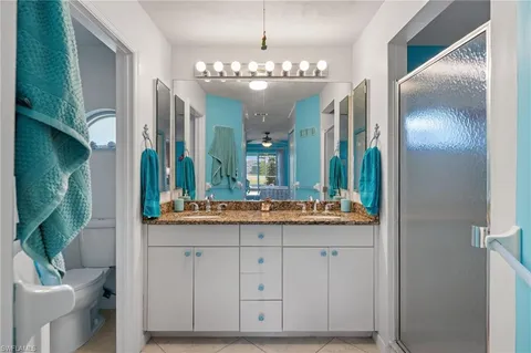 a bathroom with a granite countertop sink a toilet and a large mirror