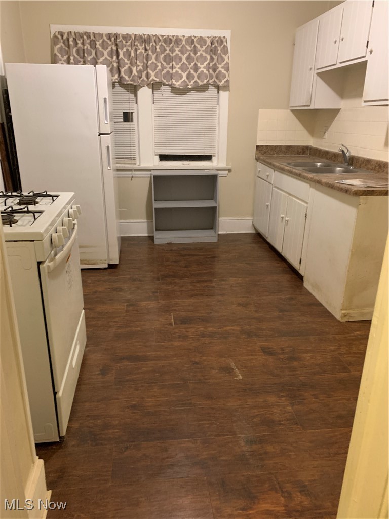 13000 Rockside Road Cleveland, OH 44125 - Photo 22 of 41 Kitchen featuring dark wood-type flooring, sink, stove, decorative backsplash, and white cabinetry