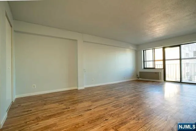 a view of an empty room with a window and wooden floor