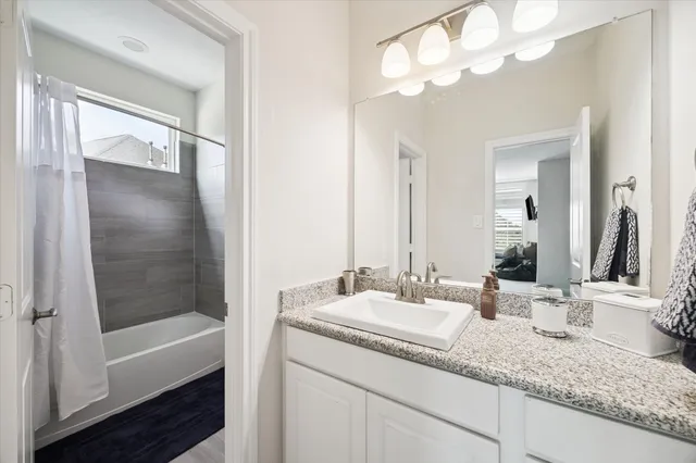 a bathroom with a granite countertop sink a mirror and a bathtub