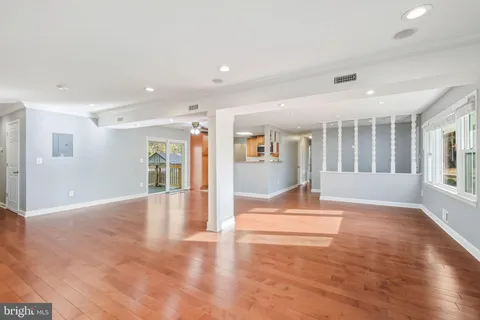 a view of an empty room with wooden floor and a window