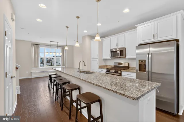 a kitchen with kitchen island granite countertop a table chairs microwave and refrigerator