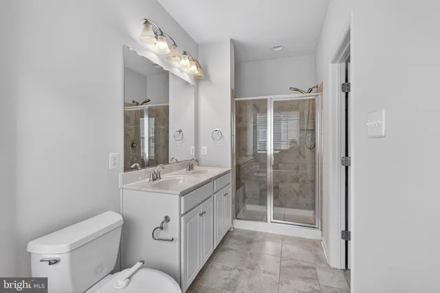 a bathroom with a granite countertop sink a mirror and a toilet