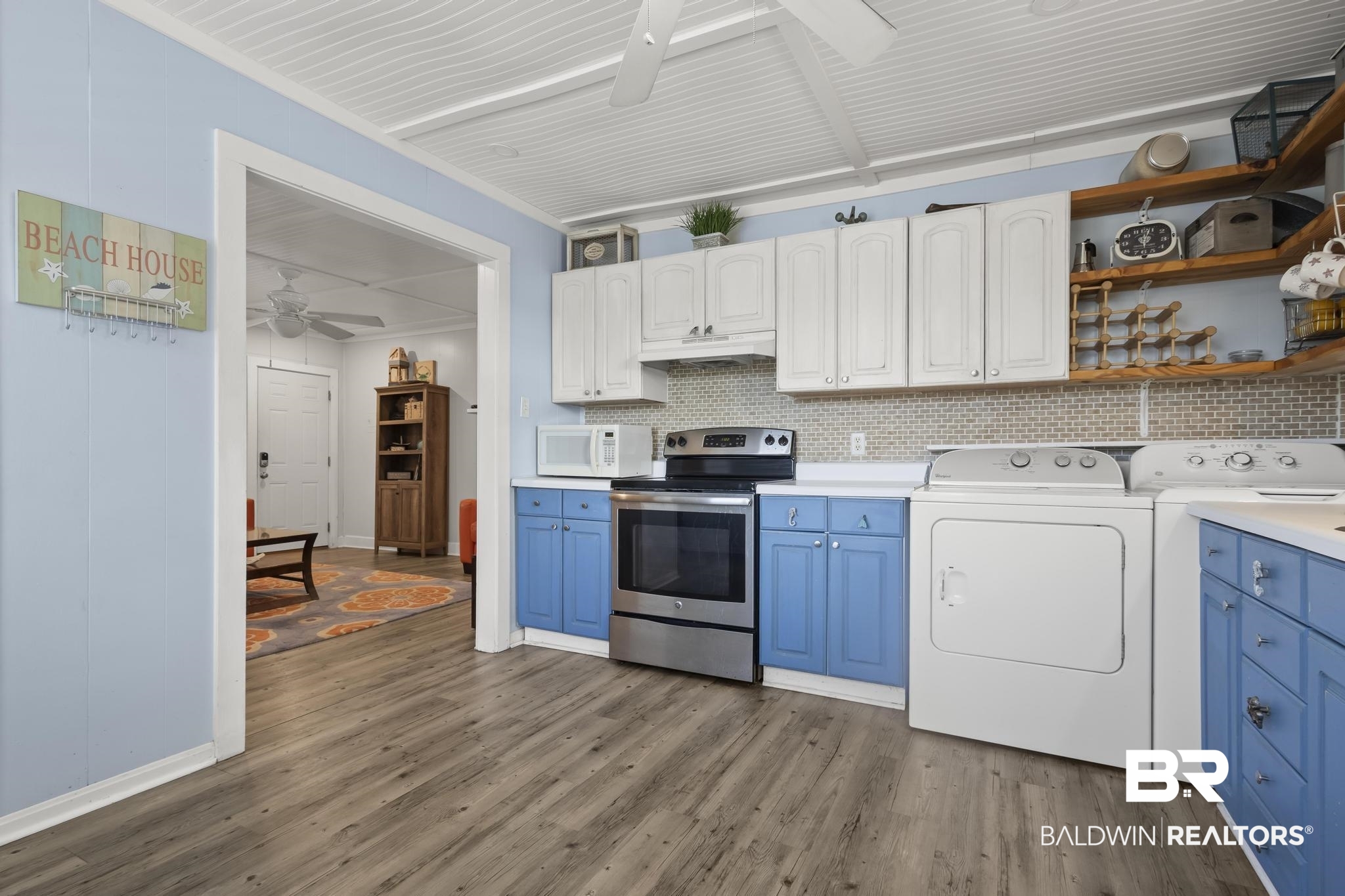 562 Veterans Road Gulf Shores, AL 36542 - Photo 7 of 32 Kitchen with stainless steel range with electric stovetop, ceiling fan, blue cabinetry, washing machine and dryer, and white microwave