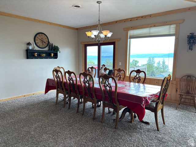 1940 East Shore Road St. Charles, ID 83272 - Photo 24 of 64 Carpeted dining room with a chandelier, wooden walls, and crown molding