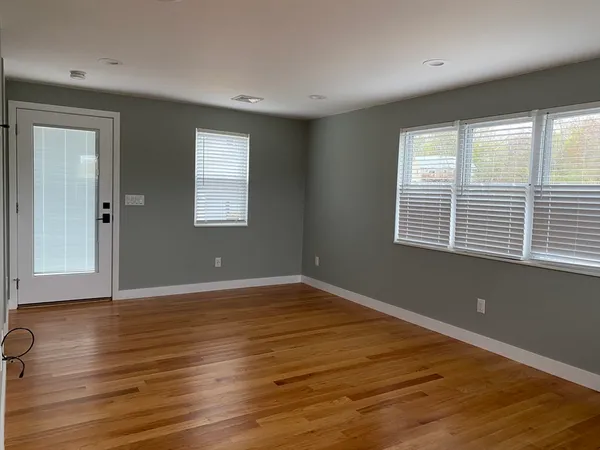 a view of an empty room with wooden floor and a window