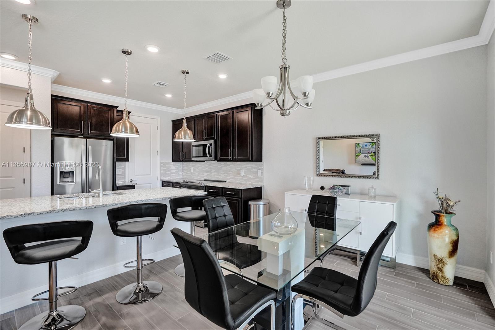 5055 Eucalyptus Drive Hollywood, FL 33021 - Photo 12 of 50 a kitchen with stainless steel appliances kitchen island granite countertop a dining table chairs and a refrigerator
