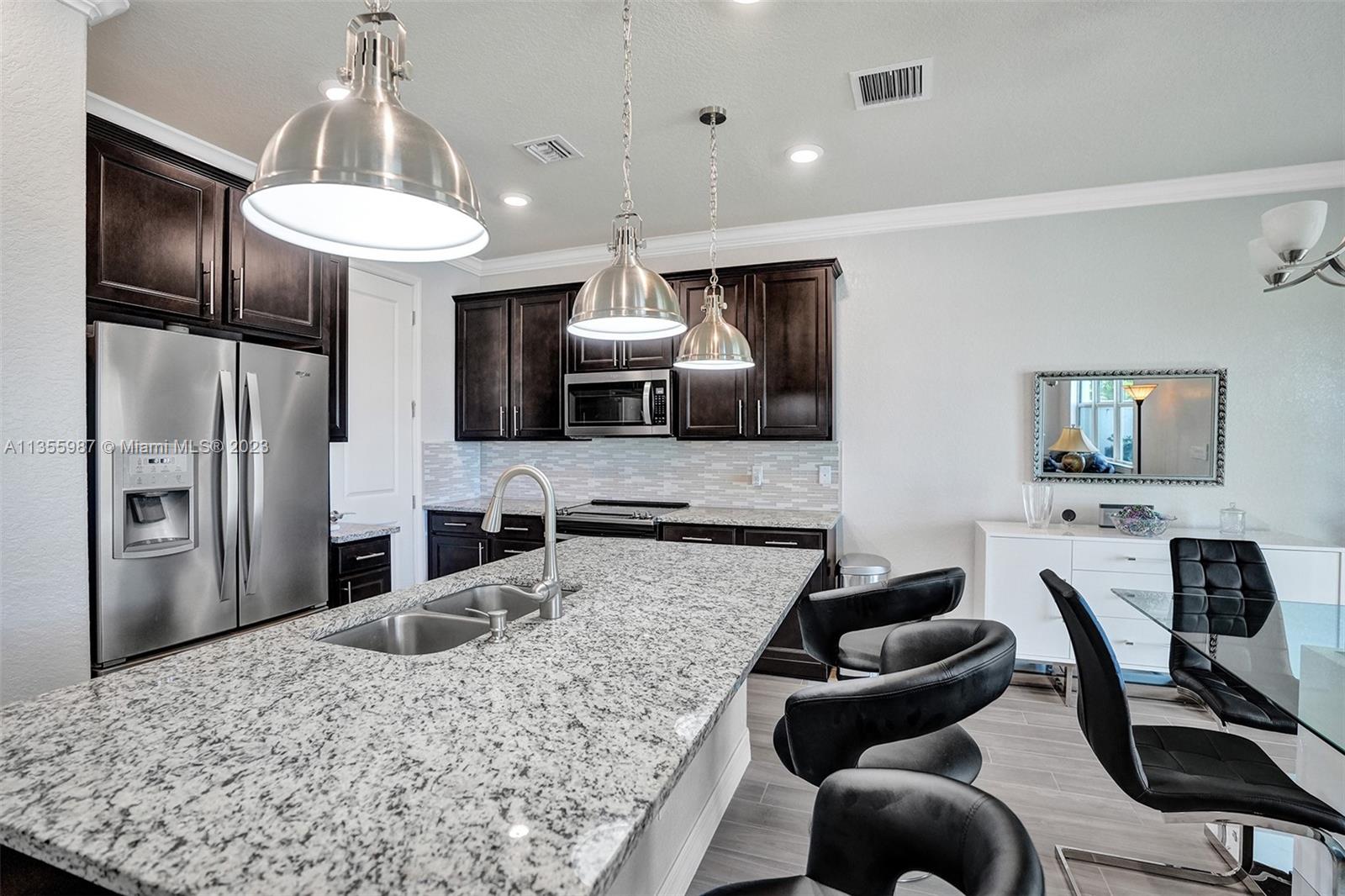 5055 Eucalyptus Drive Hollywood, FL 33021 - Photo 14 of 50 a kitchen with stainless steel appliances kitchen island granite countertop a refrigerator oven a sink a dining table and chairs with wooden floor