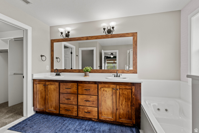 75 East 200 North Mendon, UT 84325 - Photo 14 of 36 Bathroom with double vanity, a jetted tub, a spacious closet, and dark colored carpet