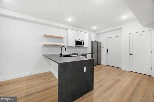 a kitchen with stainless steel appliances granite countertop a refrigerator a sink dishwasher and a stove with wooden floor