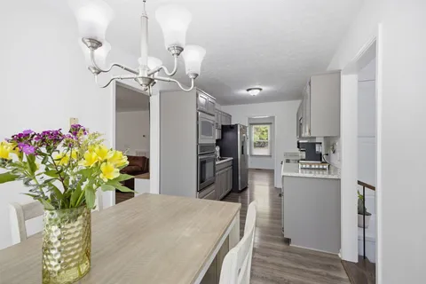 a kitchen with stainless steel appliances kitchen island granite countertop furniture a refrigerator a stove a oven with white cabinets