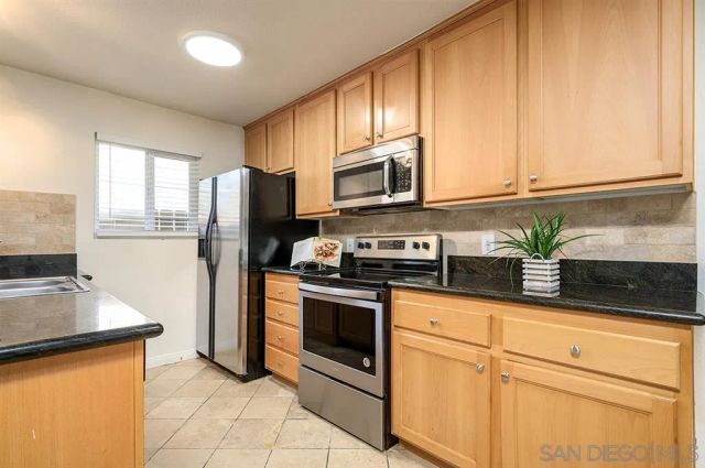 a kitchen with granite countertop white cabinets stainless steel appliances and a window