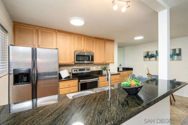 a kitchen with stainless steel appliances granite countertop a refrigerator a stove a sink a dining table and chairs with wooden floor