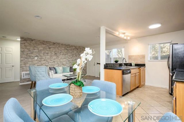 a kitchen with stainless steel appliances kitchen island granite countertop a table chairs and a refrigerator