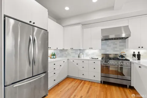 a kitchen with white cabinets and wooden floor