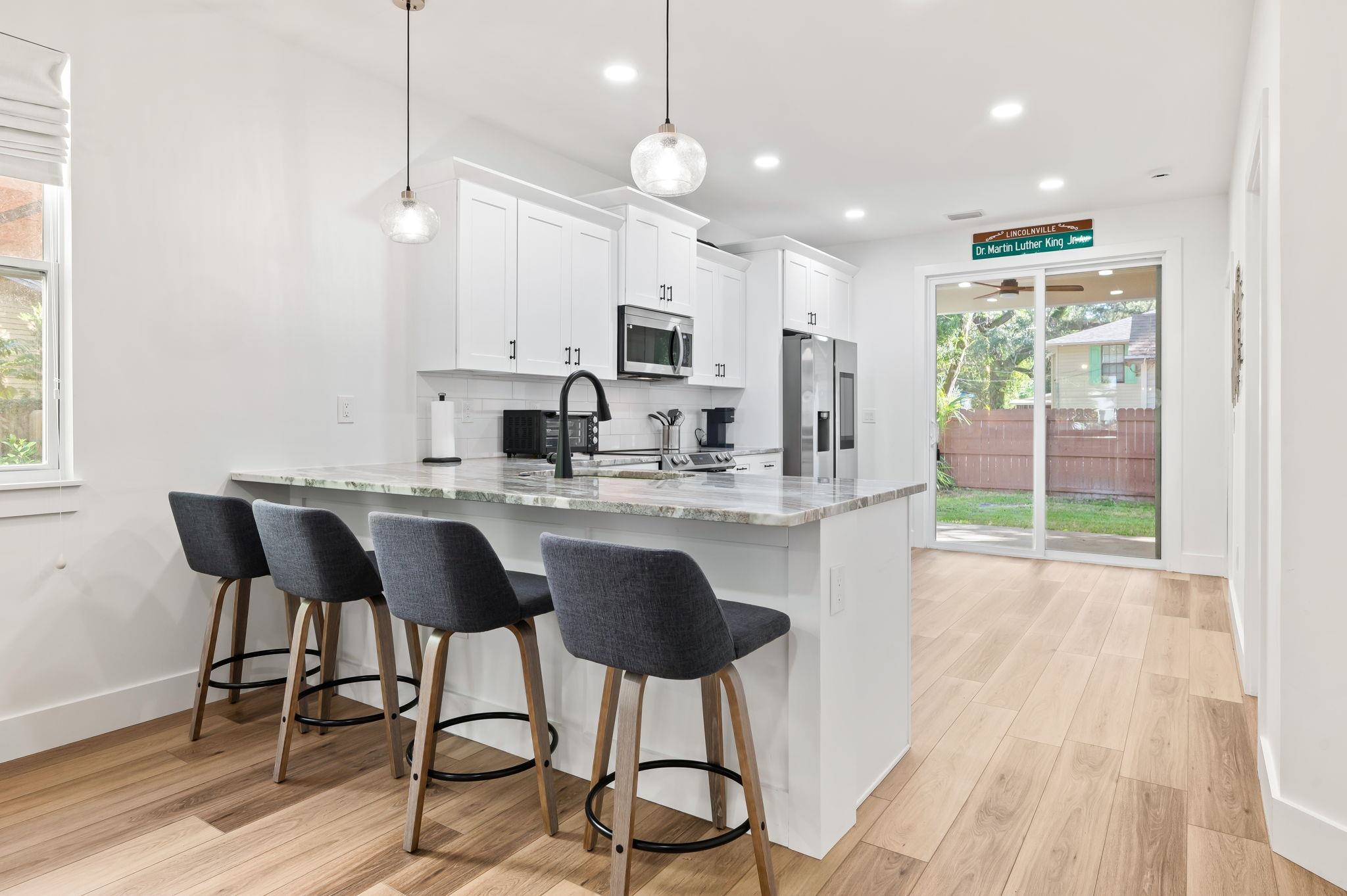 135 Blanco Street St. Augustine, FL 32084 - Photo 14 of 35 a kitchen with stainless steel appliances granite countertop a stove a sink a microwave a dining table and chairs with wooden floor