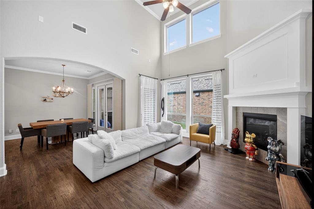 1039 Stephen Street Allen, TX 75013 - Photo 10 of 40 Living area featuring ornamental molding, arched walkways, dark wood finished floors, a high ceiling, and a tiled fireplace