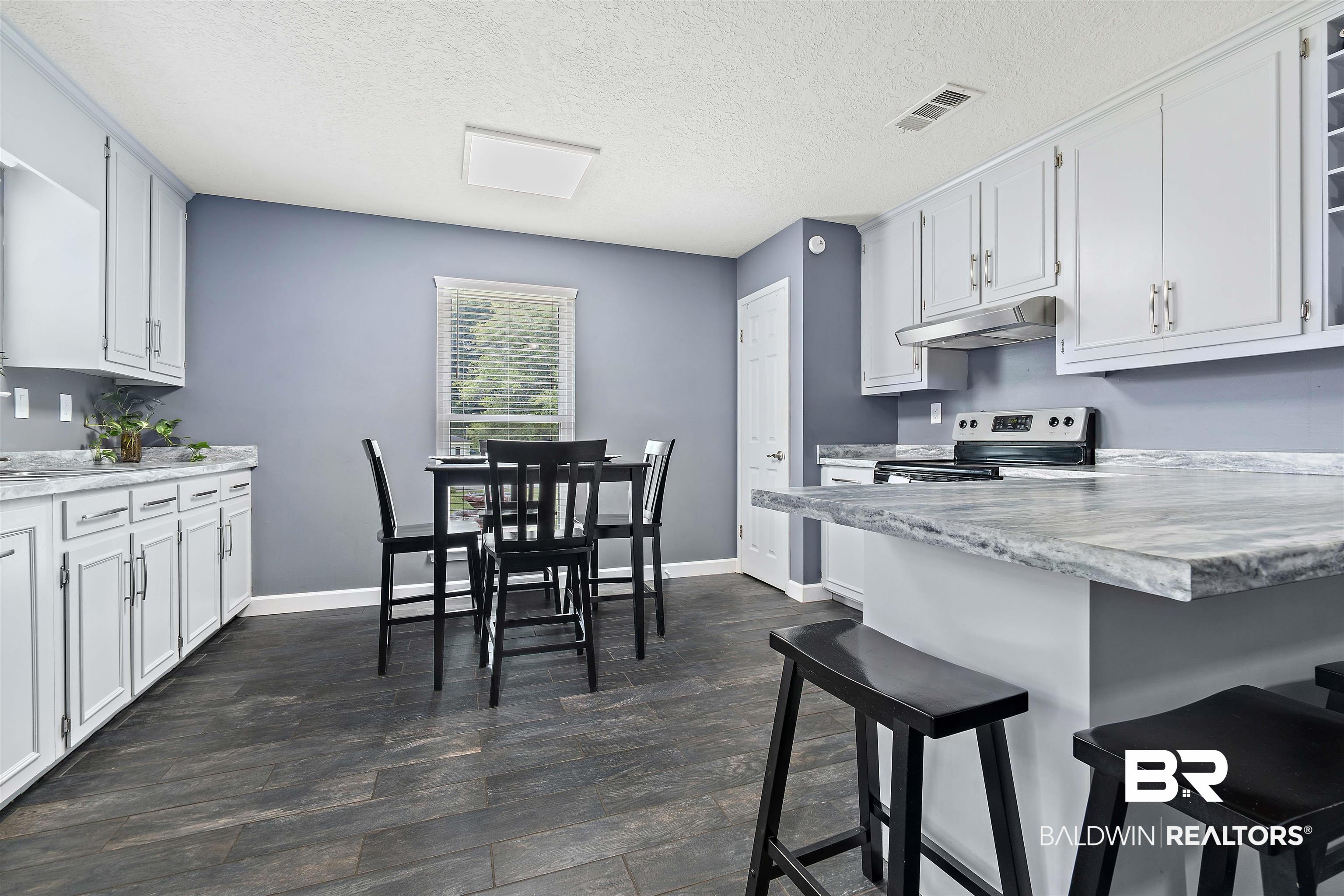 2000 Campfire Drive Semmes, AL 36575 - Photo 8 of 26 Kitchen with stainless steel range with electric stovetop, white cabinetry, and dark wood-type flooring
