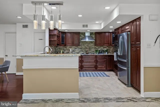 a kitchen with kitchen island a counter top space a sink stainless steel appliances and cabinets