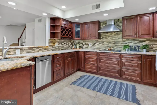a kitchen with stainless steel appliances granite countertop wooden cabinets a sink and dishwasher a stove with wooden floor