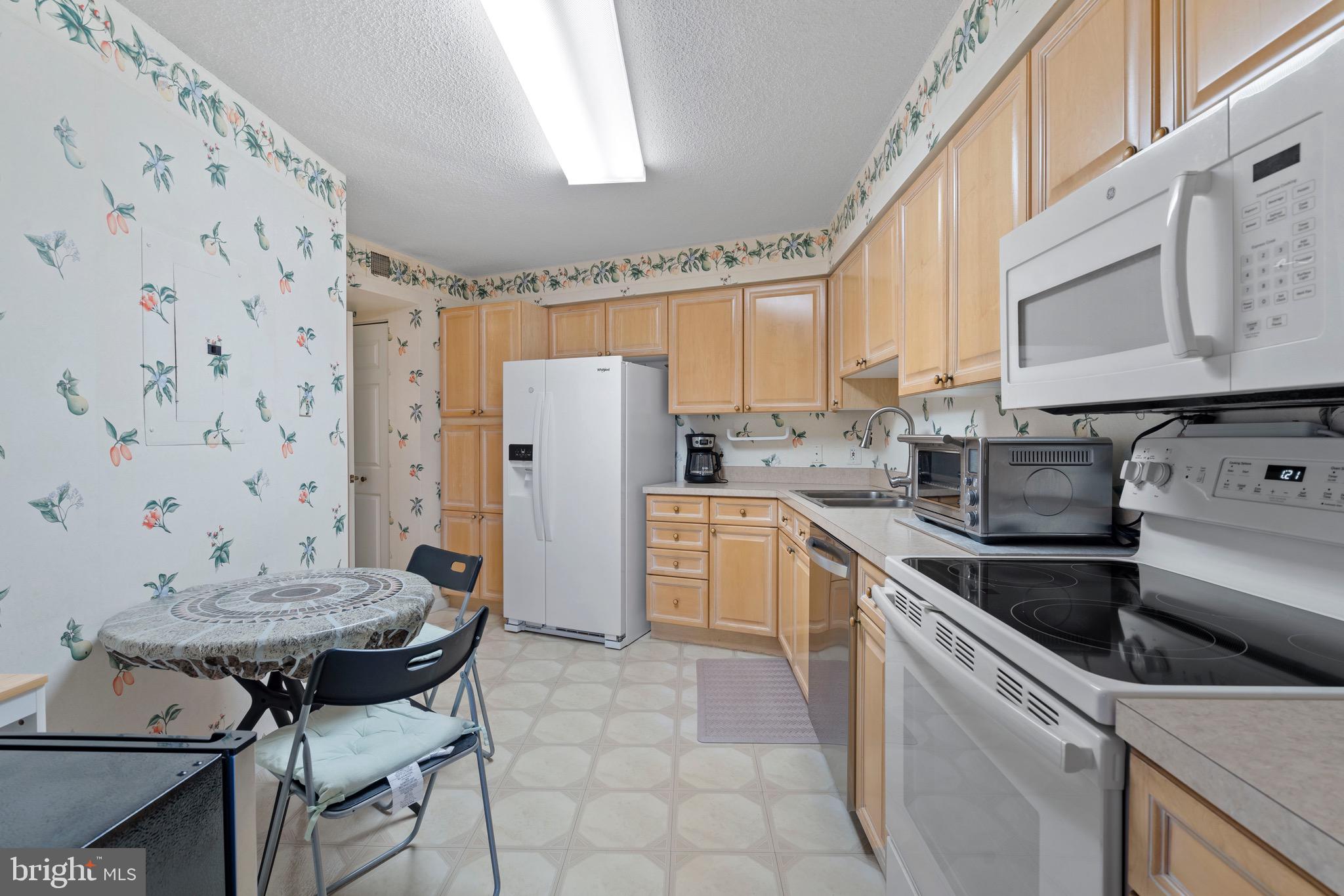 19385 Cypress Ridge Terrace, Unit 914 Leesburg, VA 20176 - Photo 13 of 39 a kitchen with a stove a refrigerator and a dining table