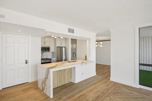 a large white kitchen with kitchen island a sink a center island stainless steel appliances and a cabinets