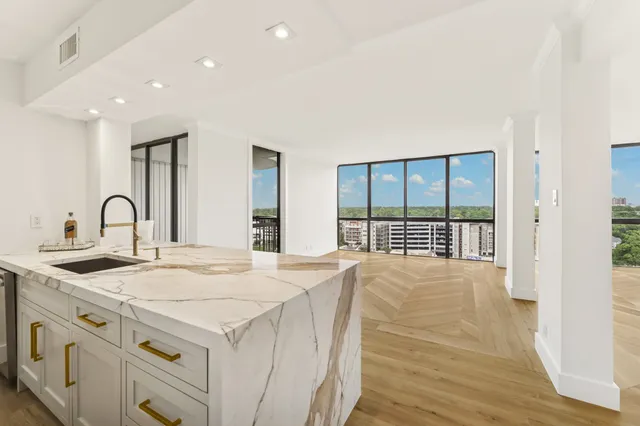 a kitchen with stainless steel appliances granite countertop a stove a sink and a large window