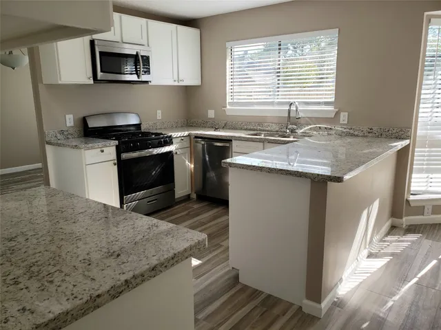 a kitchen with stainless steel appliances granite countertop a sink stove and microwave