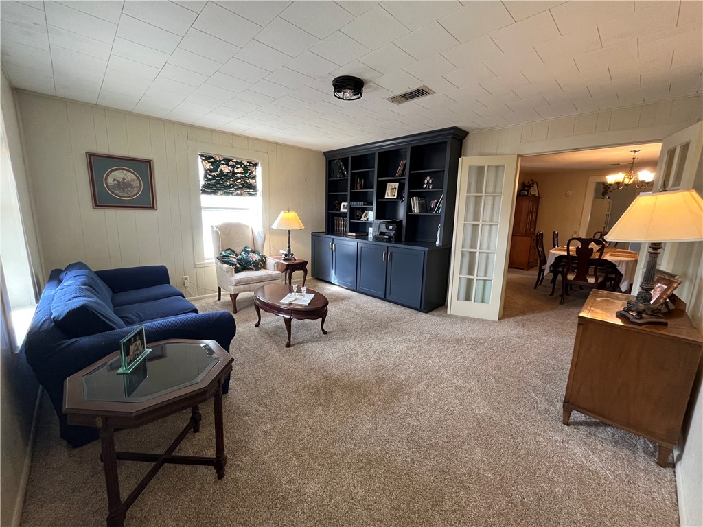 1102 North Travis Avenue Cameron, TX 76520 - Photo 5 of 48 Living area featuring light carpet, a chandelier, and wood walls