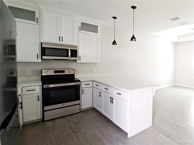 a kitchen with stainless steel appliances white cabinets and a wooden floor