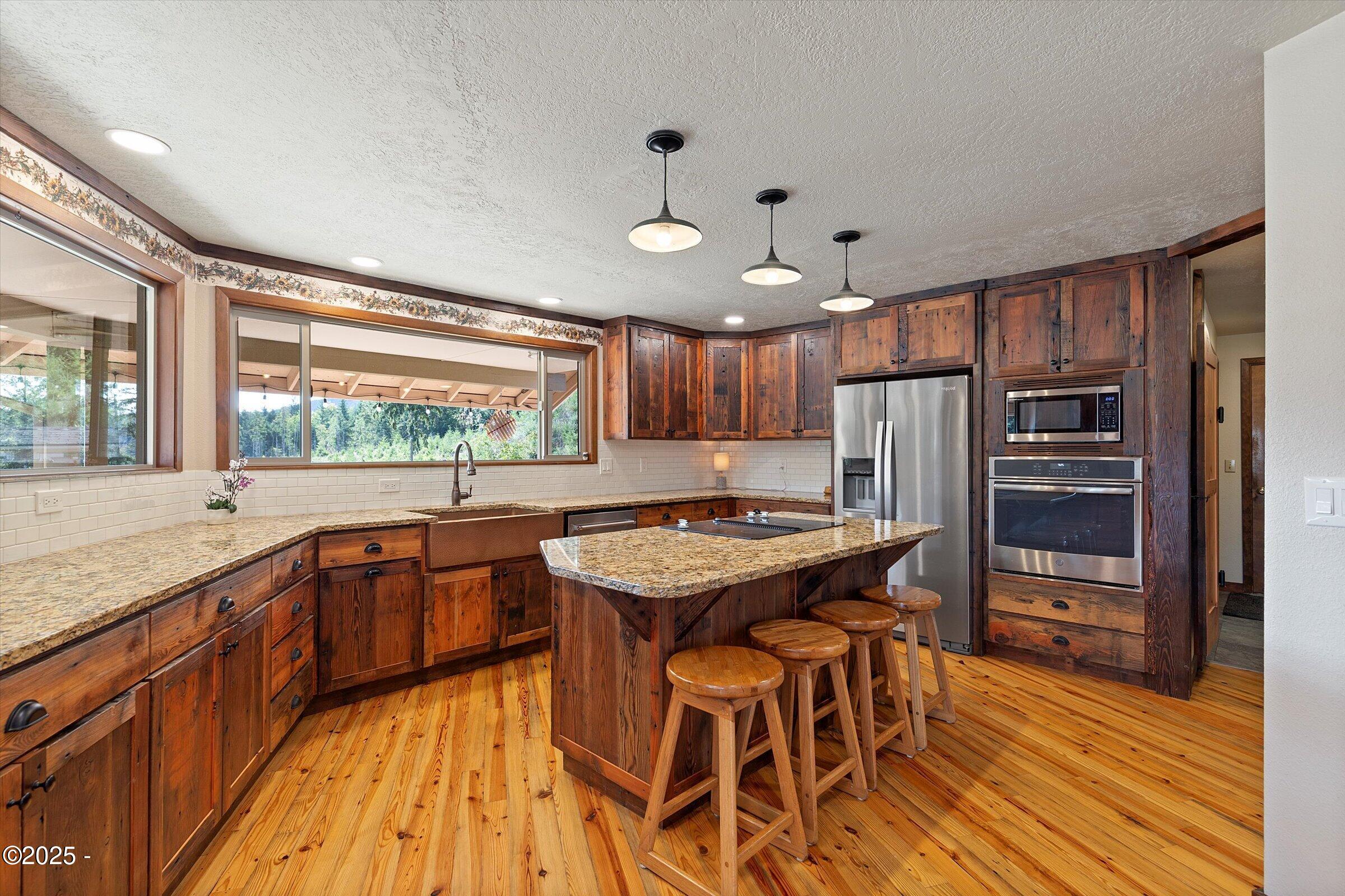 21560 Gooseneck Road Sheridan, OR 97378 - Photo 20 of 63 a kitchen with stainless steel appliances granite countertop wooden floor window and cabinets
