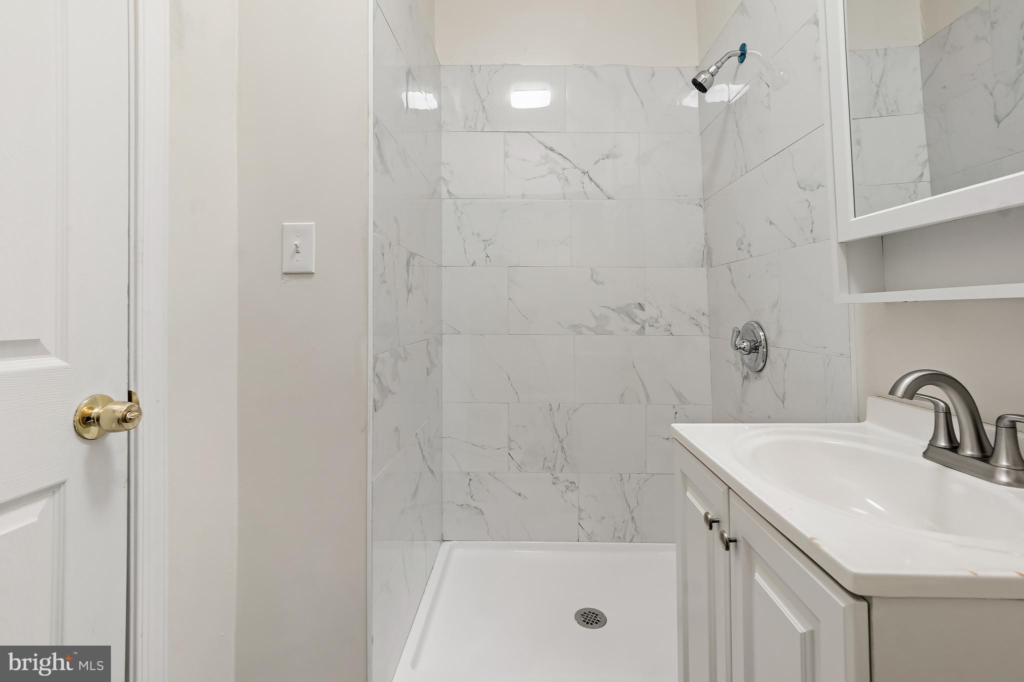 2427 East Lanvale Street Baltimore, MD 21213 - Photo 14 of 29 a bathroom with a shower a sink and mirror