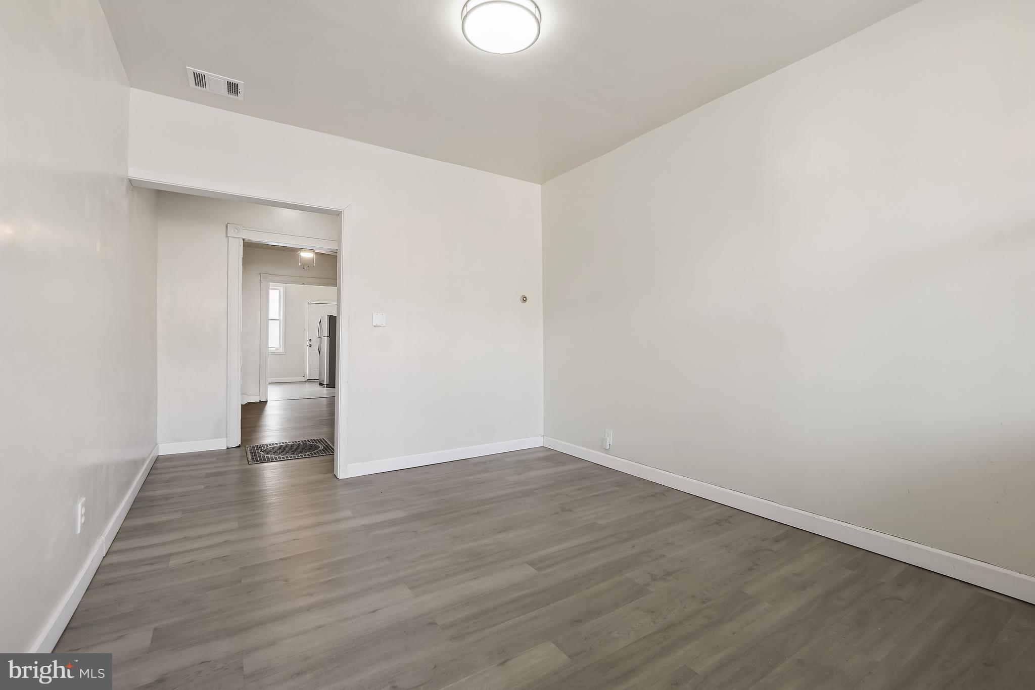 2427 East Lanvale Street Baltimore, MD 21213 - Photo 6 of 29 a view of an empty room with wooden floor and a mirror