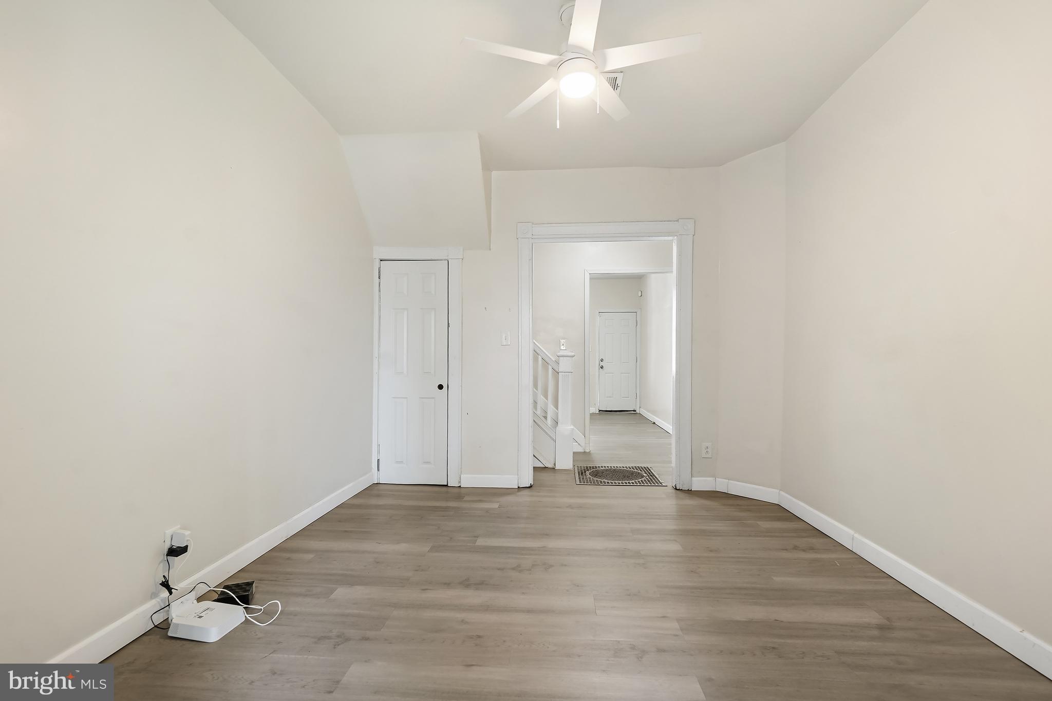 2427 East Lanvale Street Baltimore, MD 21213 - Photo 7 of 29 an empty room with wooden floor and a ceiling fan