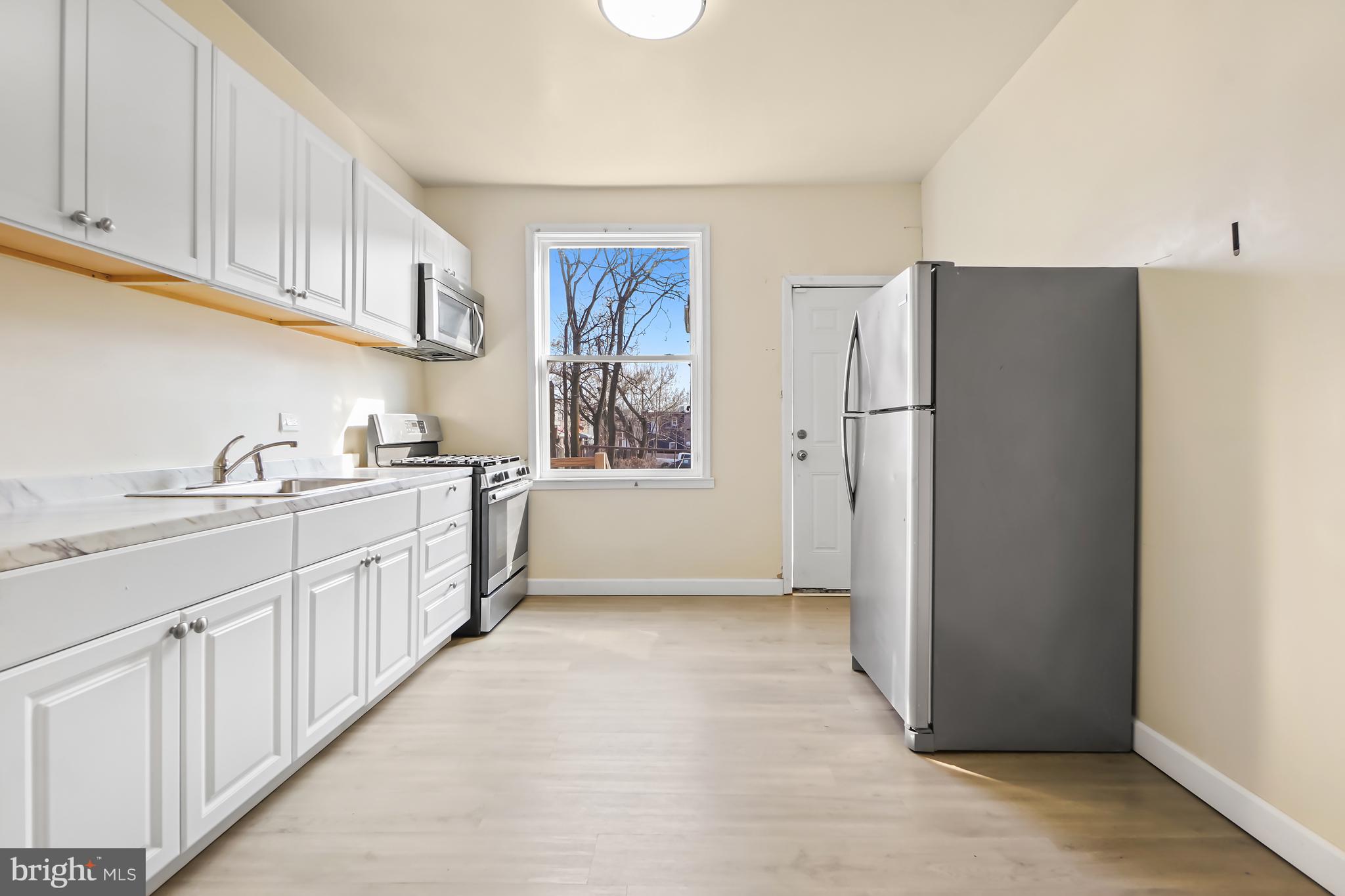 2427 East Lanvale Street Baltimore, MD 21213 - Photo 8 of 29 a kitchen with white cabinets and refrigerator