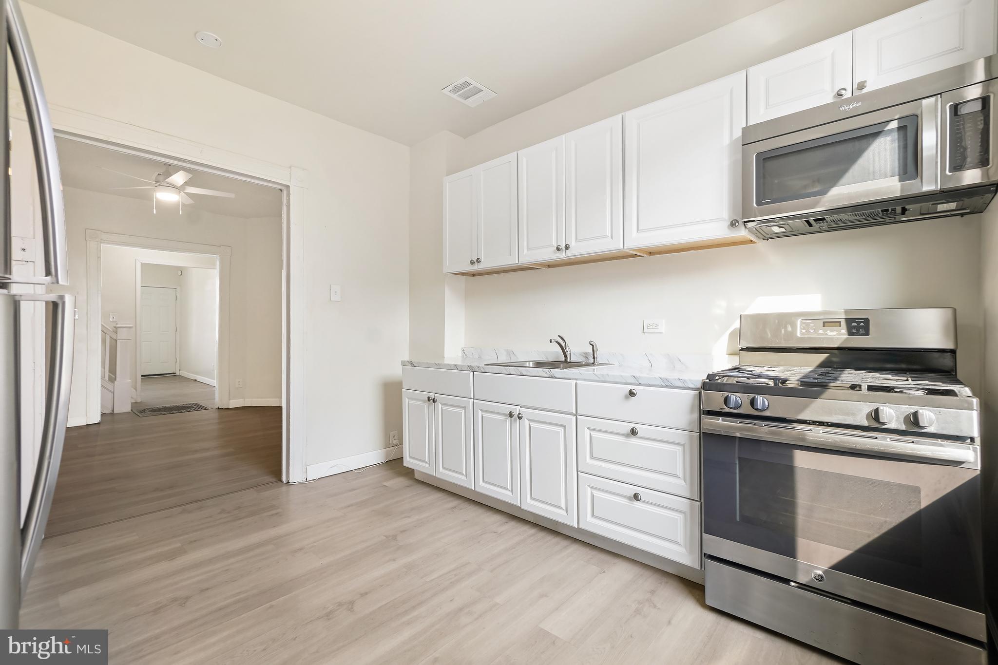2427 East Lanvale Street Baltimore, MD 21213 - Photo 10 of 29 a kitchen with granite countertop white cabinets and stainless steel appliances
