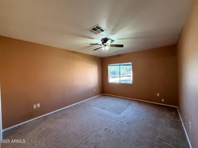 an empty room with a window and a ceiling fan