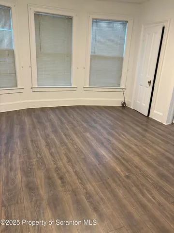 an empty room with wooden floor and window