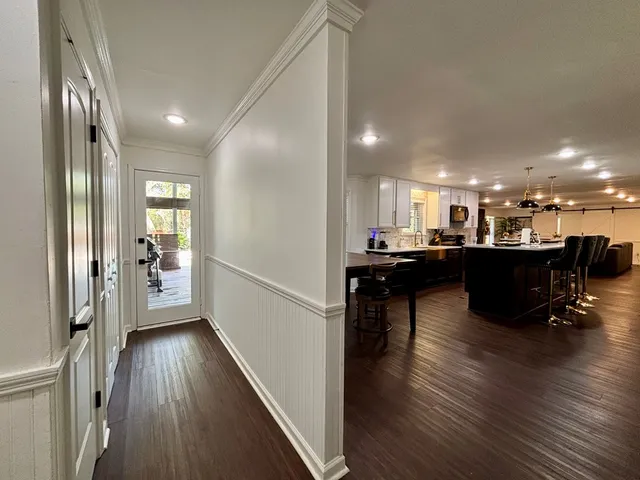 a dining hall with stainless steel appliances granite countertop a refrigerator a sink dishwasher a dining table and chairs with wooden floor