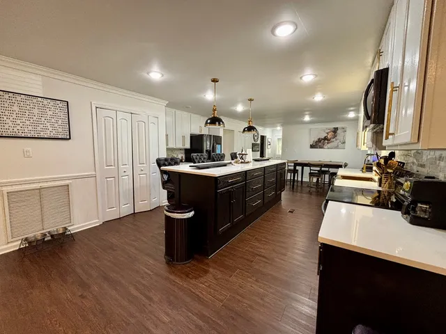 a kitchen with stainless steel appliances granite countertop a sink a stove and a wooden floors