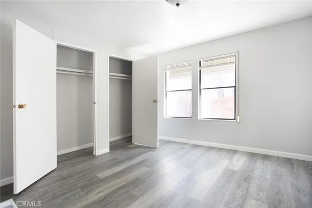 an empty room with wooden floor closet and windows